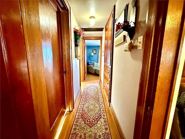 hall featuring light wood-type flooring and baseboards