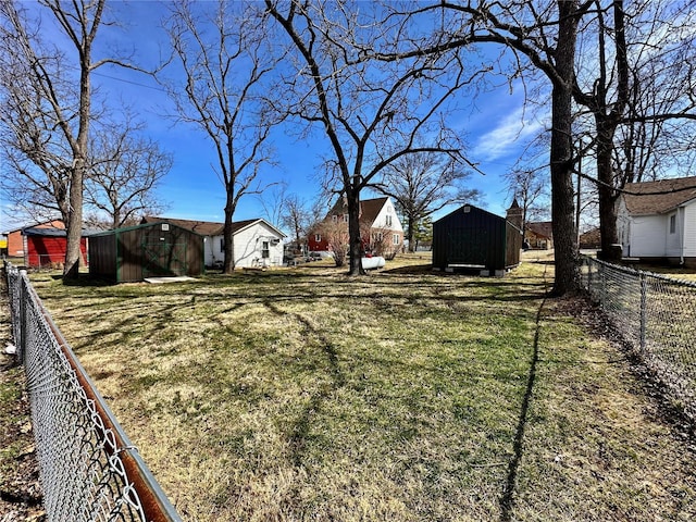 view of yard with a storage shed, an outbuilding, and fence