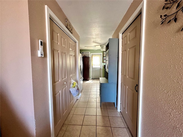 hallway with light tile patterned floors and a textured wall