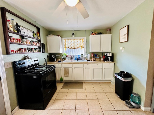 kitchen with light tile patterned flooring, a sink, light countertops, black range with electric cooktop, and white cabinetry