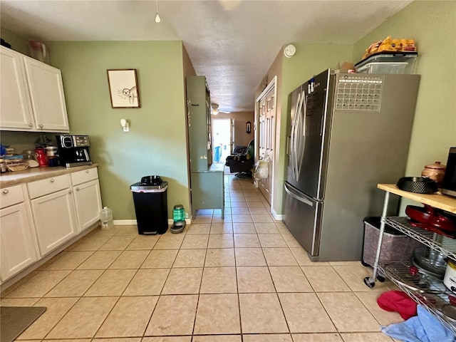 kitchen with light tile patterned floors, white cabinetry, freestanding refrigerator, and baseboards