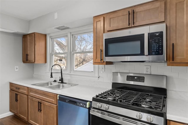 kitchen with a sink, light countertops, tasteful backsplash, and stainless steel appliances