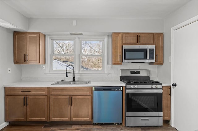 kitchen featuring tasteful backsplash, appliances with stainless steel finishes, light countertops, and a sink