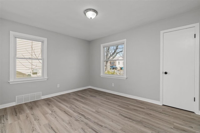 unfurnished room featuring wood finished floors, baseboards, and visible vents