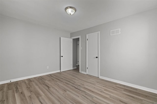 empty room with light wood-style flooring, baseboards, and visible vents