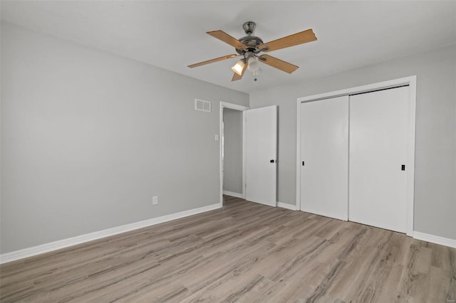 unfurnished bedroom with visible vents, wood finished floors, a closet, baseboards, and ceiling fan