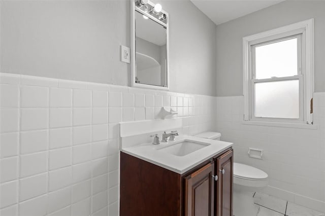 bathroom featuring tile walls, toilet, wainscoting, marble finish floor, and vanity