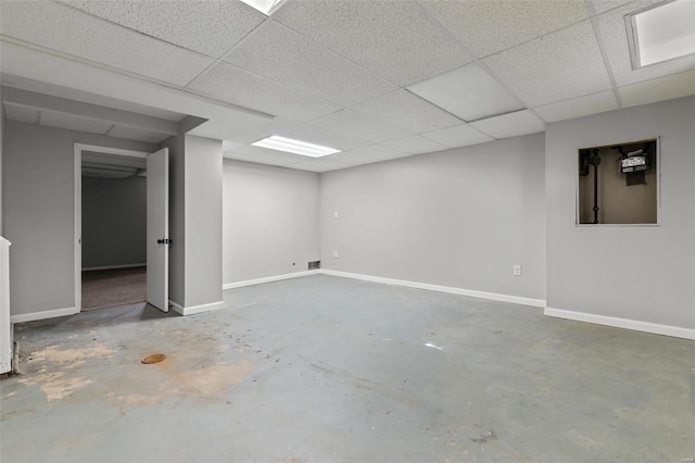 finished below grade area featuring a paneled ceiling and baseboards