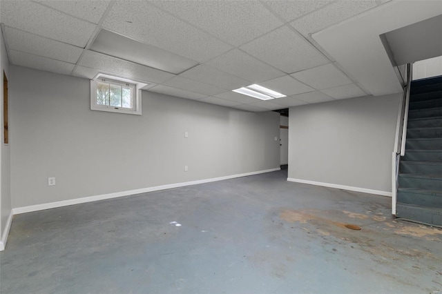 below grade area with stairs, a paneled ceiling, and baseboards