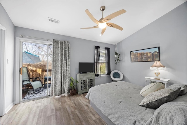 bedroom with visible vents, vaulted ceiling, wood finished floors, a ceiling fan, and access to outside