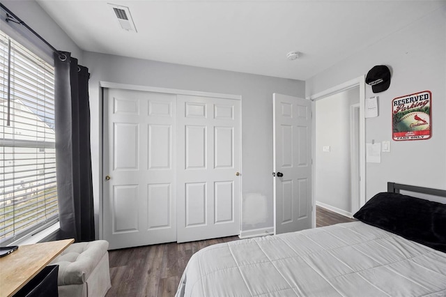 bedroom featuring a closet, visible vents, baseboards, and dark wood-style flooring