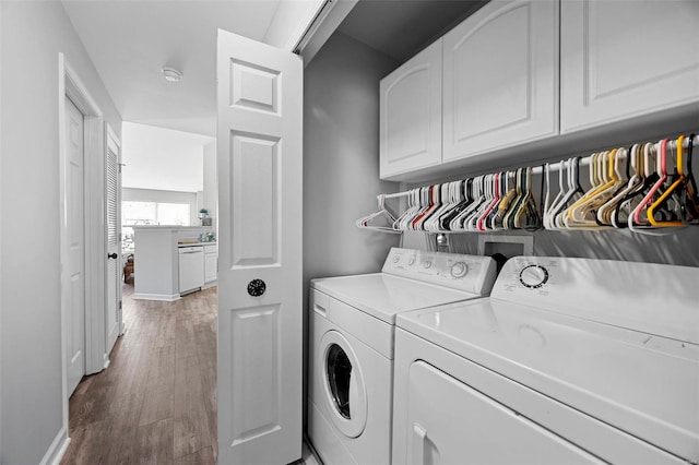 washroom with separate washer and dryer, cabinet space, light wood-style floors, and baseboards