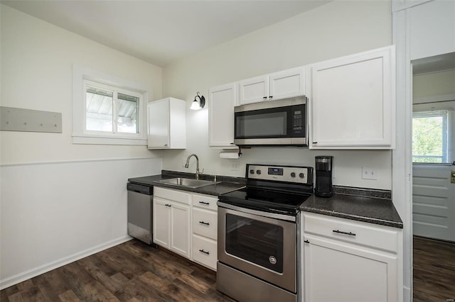 kitchen featuring a sink, dark countertops, dark wood finished floors, white cabinetry, and stainless steel appliances