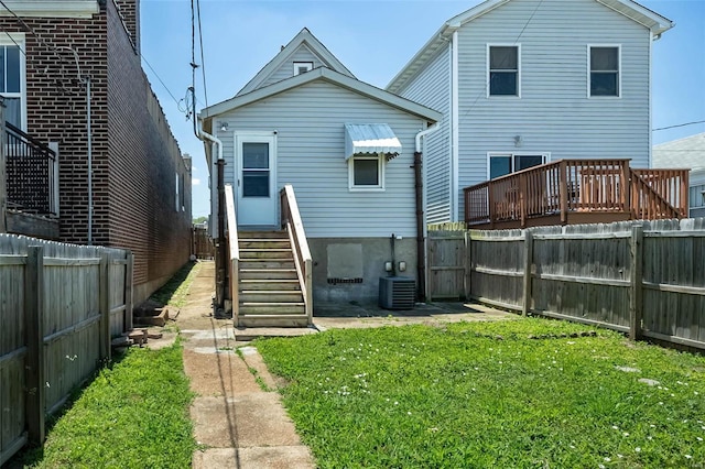 back of house featuring central AC unit, a fenced backyard, and a lawn