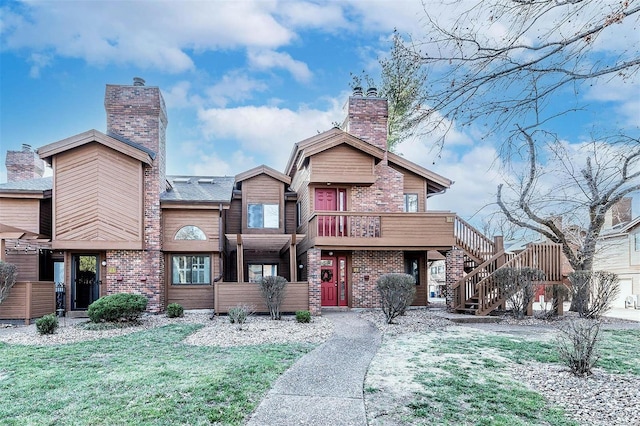 view of front of house with stairs, a front yard, and a chimney