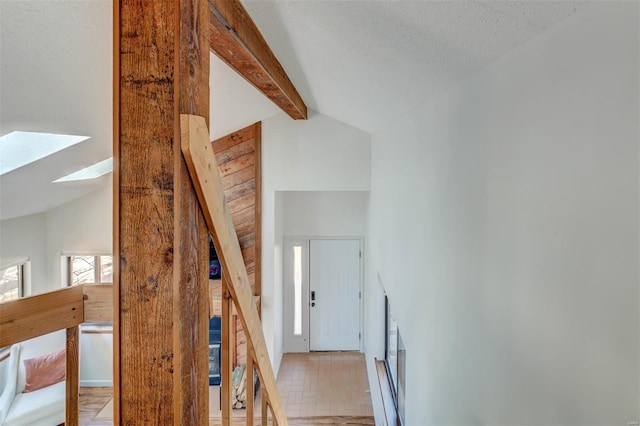 staircase featuring beam ceiling, high vaulted ceiling, and a skylight