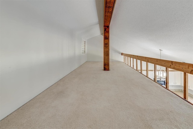 carpeted spare room featuring a textured ceiling and vaulted ceiling with beams