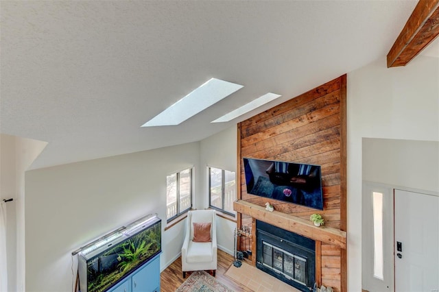 living area featuring a large fireplace, lofted ceiling with beams, and wood finished floors