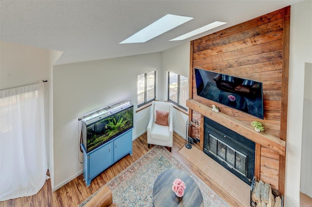 living room featuring baseboards, lofted ceiling, wood finished floors, and a fireplace