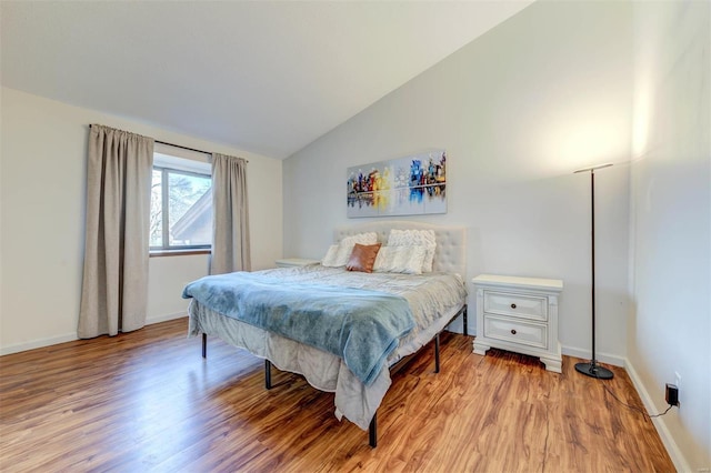 bedroom featuring lofted ceiling, light wood-style flooring, and baseboards