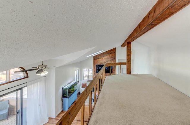 interior space featuring lofted ceiling with beams, light colored carpet, and a textured ceiling