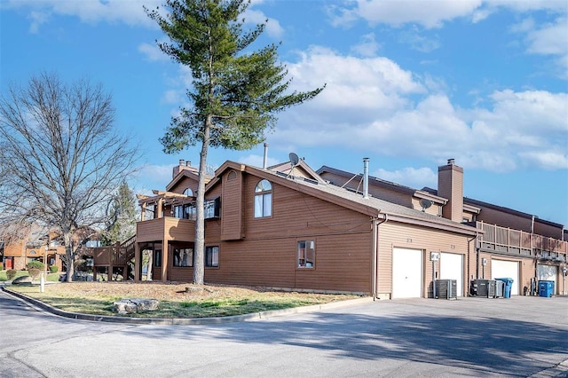 view of property exterior with central AC unit, a garage, and a chimney