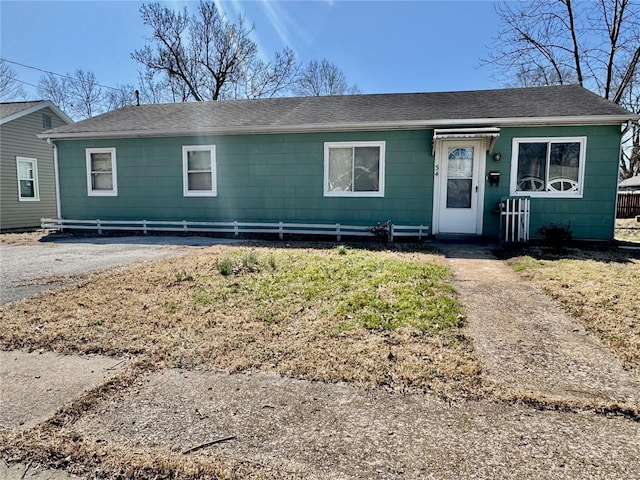 view of front of home featuring driveway, a shingled roof, and fence