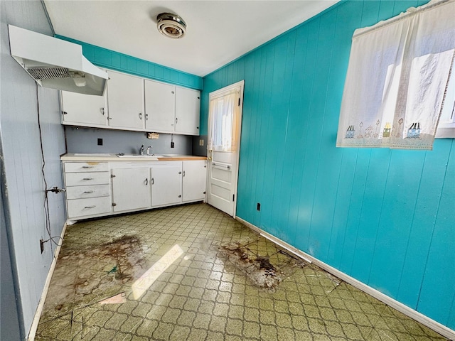 kitchen featuring tile patterned floors, a sink, white cabinetry, light countertops, and baseboards