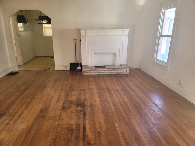 unfurnished living room with baseboards, wood-type flooring, and a fireplace