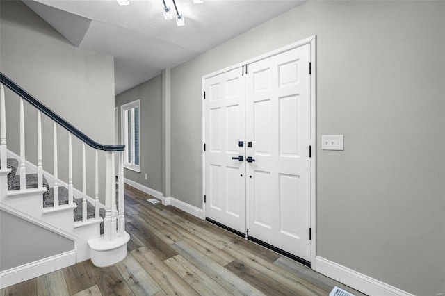 entryway featuring stairs, wood finished floors, and baseboards