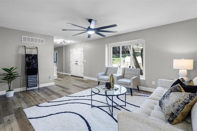 living area featuring ceiling fan, wood finished floors, visible vents, and baseboards