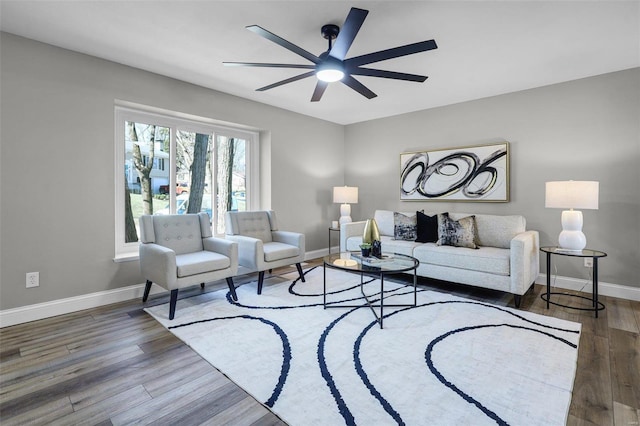 living area with a ceiling fan, baseboards, and wood finished floors