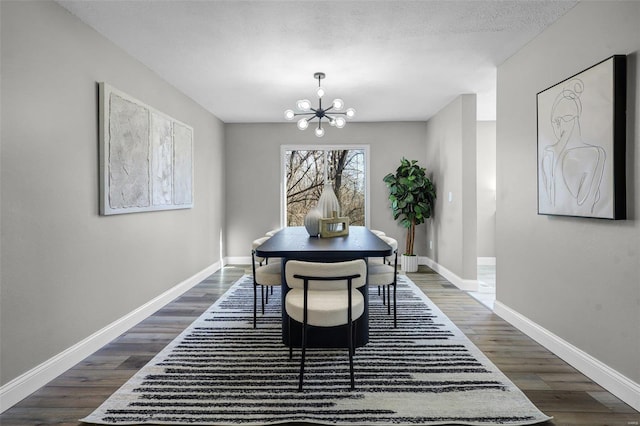 dining room featuring dark wood finished floors, an inviting chandelier, a textured ceiling, and baseboards