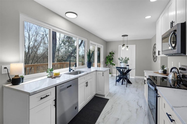 kitchen featuring white cabinets, light stone counters, appliances with stainless steel finishes, and a sink