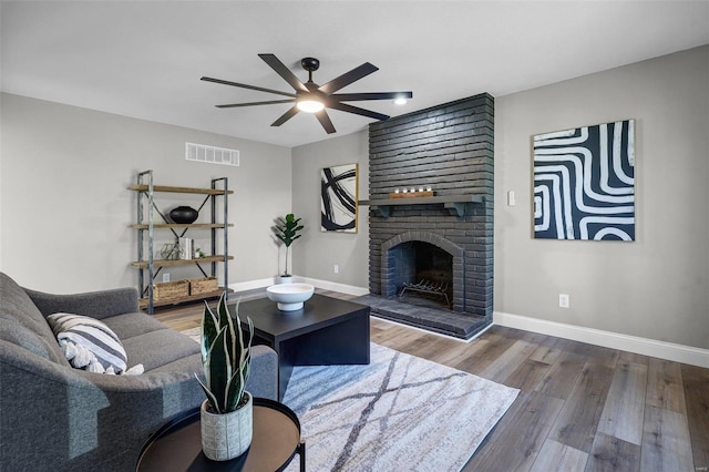 living room with visible vents, a fireplace, baseboards, and wood finished floors