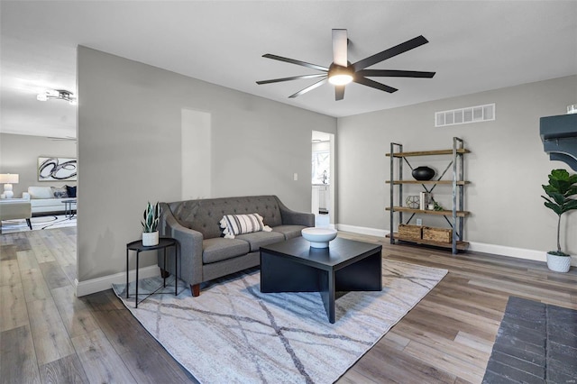 living room featuring visible vents, ceiling fan, baseboards, and wood finished floors