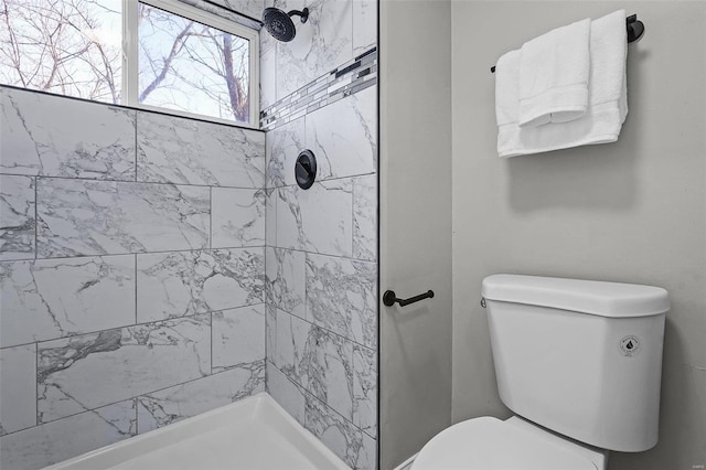 full bathroom featuring tiled shower and toilet