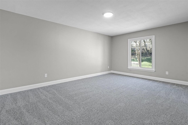 spare room featuring dark colored carpet, baseboards, and a textured ceiling