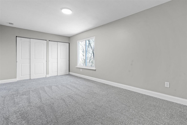 unfurnished bedroom featuring baseboards, multiple closets, and carpet floors