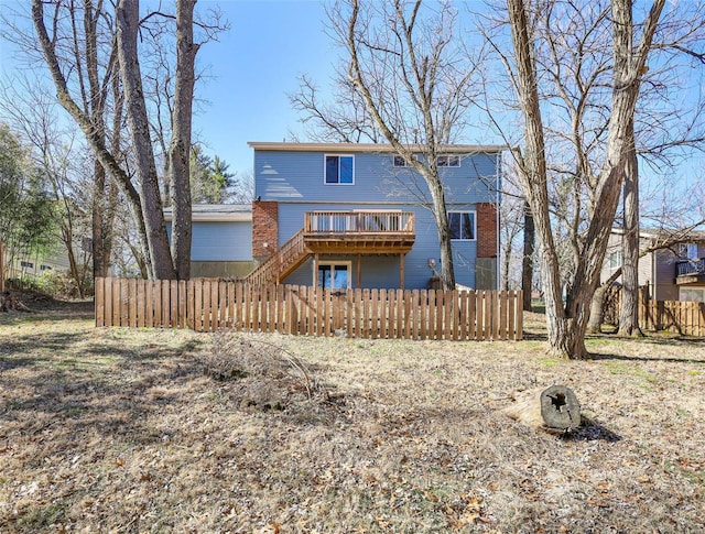 back of house with a fenced front yard, stairway, a wooden deck, and brick siding