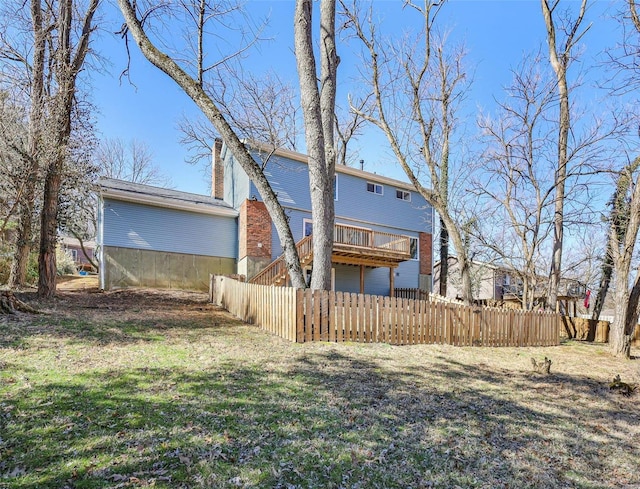 rear view of house featuring a lawn, fence, stairway, a wooden deck, and a chimney