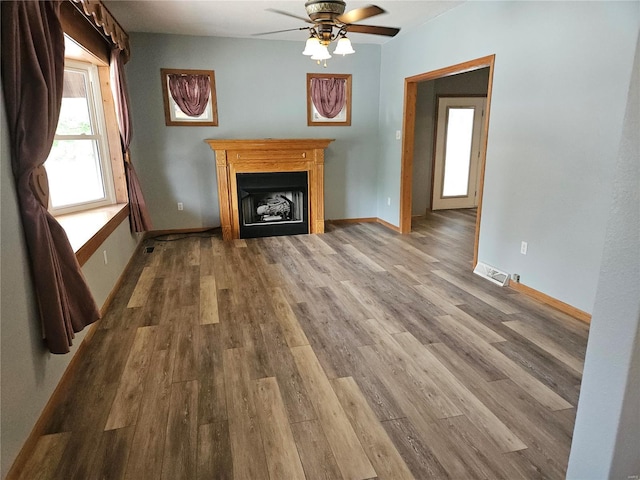 unfurnished living room featuring visible vents, wood finished floors, a fireplace, baseboards, and ceiling fan