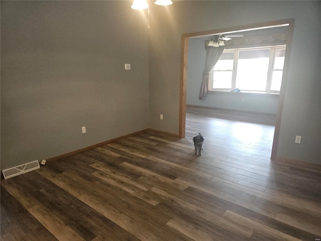 spare room with visible vents, baseboards, dark wood-type flooring, and ceiling fan