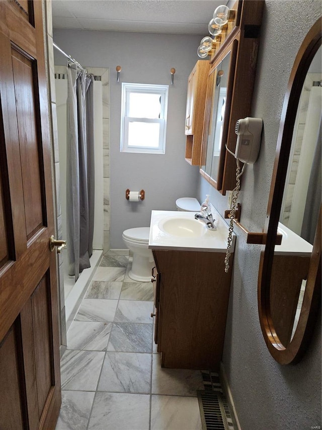 bathroom featuring curtained shower, toilet, marble finish floor, and vanity