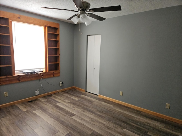 empty room featuring visible vents, ceiling fan, baseboards, wood finished floors, and a textured ceiling