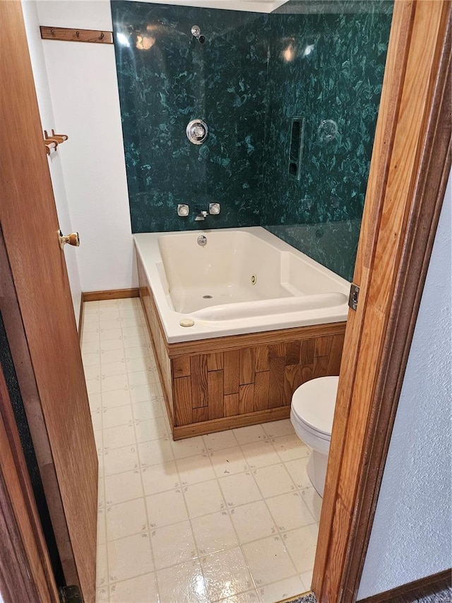 bathroom featuring tile patterned floors, a tub with jets, and toilet