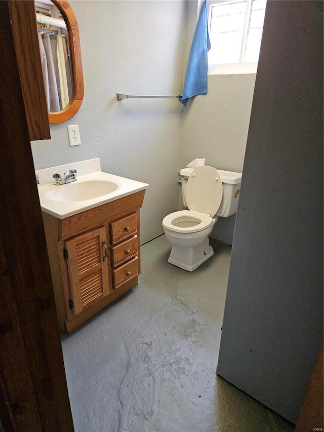 bathroom with vanity, toilet, and concrete flooring