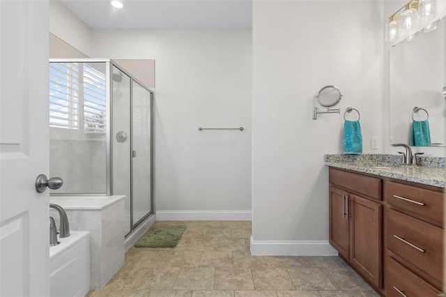 bathroom with a bath, a shower stall, vanity, and baseboards