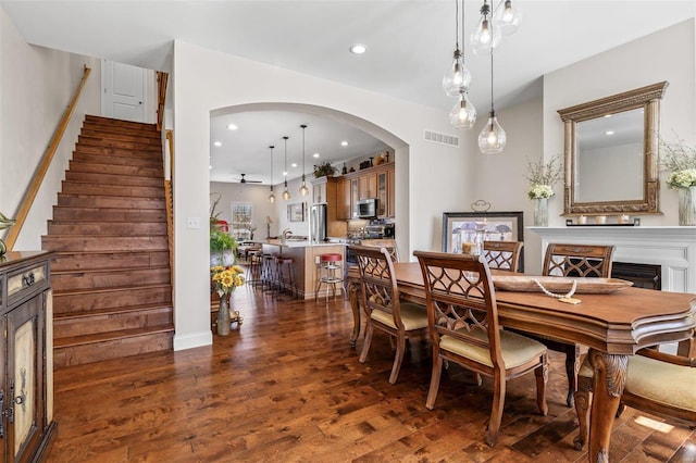 dining space with visible vents, recessed lighting, arched walkways, dark wood-style flooring, and stairs