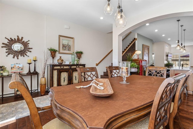 dining area featuring recessed lighting, arched walkways, dark wood-type flooring, and stairs